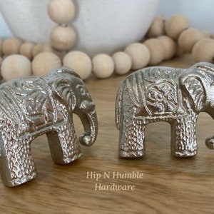 May include: Two silver elephant drawer pulls with intricate details. The elephant pulls are a decorative accent for furniture.