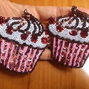 Puede incluir: Dos parches en forma de cupcake rosa y marrón con glaseado blanco y chispas rojas y marrones. Los parches están hechos de lentejuelas y son perfectos para agregar un toque de fantasía a la ropa o los accesorios.