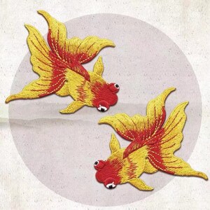 May include: Two embroidered goldfishes with red and yellow details. The fish are facing opposite directions and have a traditional Japanese style.