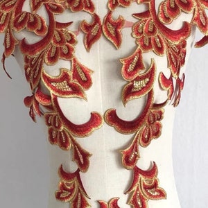 May include: Red and gold floral lace applique with a delicate design. This intricate embellishment is perfect for adding a touch of elegance to clothing, accessories, or home decor projects.