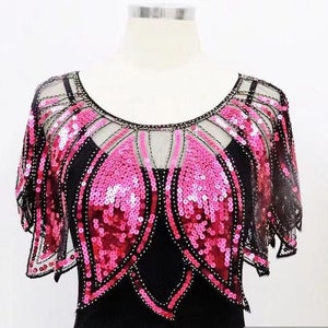 Puede incluir: Un chal de lentejuelas rosa y negro con una superposición transparente. El chal tiene un borde festoneado y un diseño delicado.