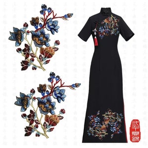May include: Two embroidered floral patches with blue, red, and gold thread. The patches feature a floral design with a branch of flowers and leaves. The patches are on a white background.