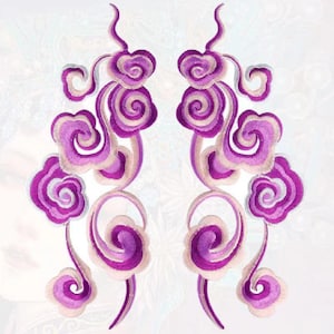 May include: Two purple and white embroidered patches featuring a swirling cloud design. The patches are symmetrical and have a delicate, intricate design.