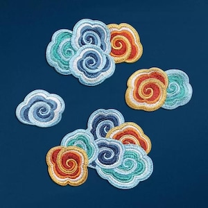 May include: A set of six embroidered iron-on patches in the shape of clouds. The patches are in shades of blue, green, orange, and red. Each cloud has a swirling design.
