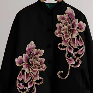 May include: Black jacket with a mandarin collar and two embroidered floral designs in shades of purple and gold.
