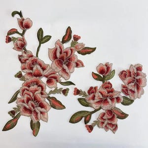 May include: Embroidered floral appliques in shades of pink and green. The appliques feature delicate flowers with intricate details.