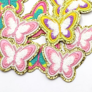 May include: A collection of colourful embroidered butterfly patches with gold glitter trim. The butterflies are pink, yellow, purple and green.