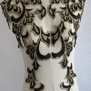 May include: Black and gold floral lace applique. The lace is delicate and intricate, with a floral design. The applique is perfect for adding a touch of elegance to any garment.