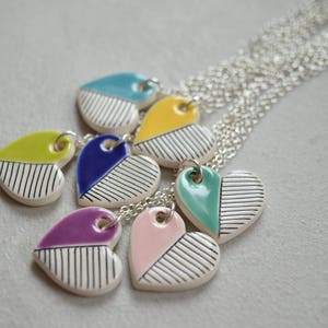 May include: A set of seven heart-shaped ceramic pendants with black and white stripes and different coloured accents. The pendants are attached to silver chains.