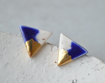 May include: A pair of triangle-shaped earrings with a white and blue glaze and gold accents.