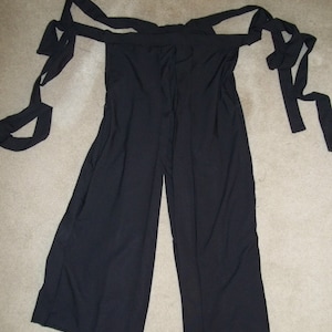 May include: Black pants with wide legs and a tie at the waist. The pants have a loose, flowing fit.