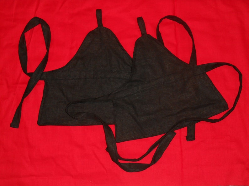 May include: Two black fabric halter tops with adjustable straps. The tops are made of a soft, woven fabric and have a simple, minimalist design.