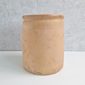 May include: A white ceramic mug with a black handle and the text "But First, Coffee" in a black, handwritten-style font. The mug is on a white surface.