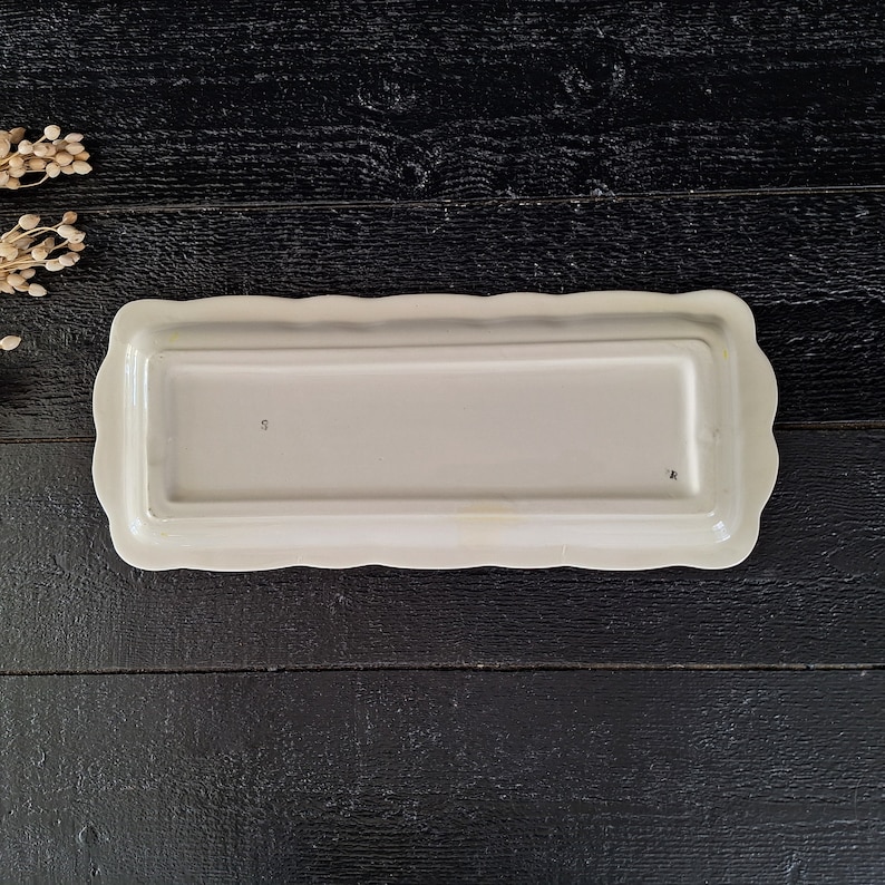 以下が含まれることがあります： 波打った縁のある白い長方形のセラミック製サービングディッシュ。ディッシュは滑らかで光沢のある仕上げで、底に「5」のマークが付いています。