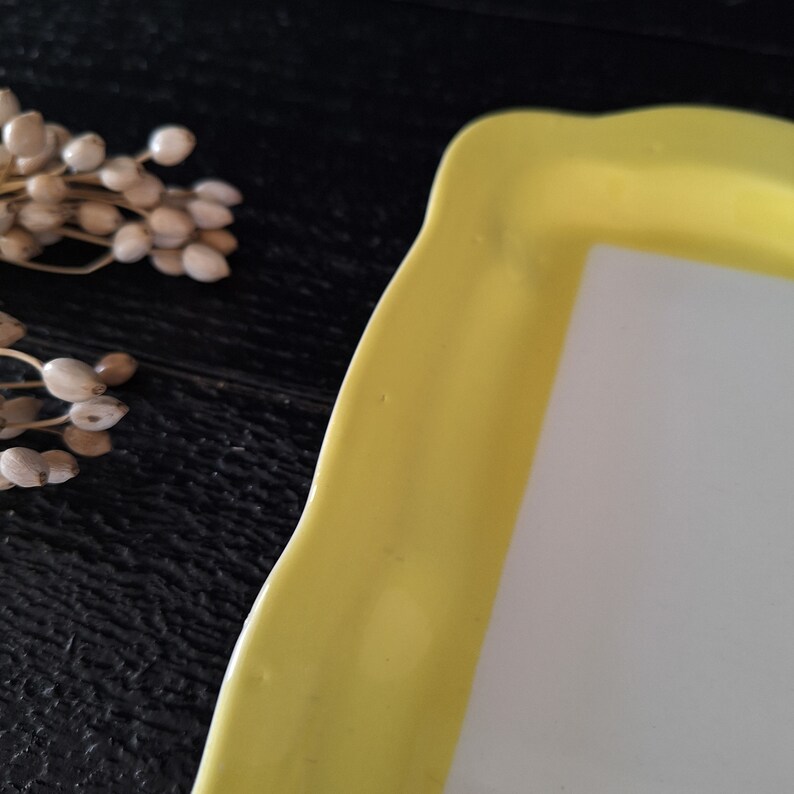 以下が含まれることがあります： 白い内側を持つ黄色いセラミック製のサービングトレイ。トレイは波状のエッジになっており、スナックやアペタイザーを提供するのに最適です。