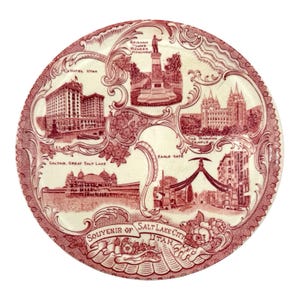 Könnte beinhalten: Ein runder Keramik-Souvenirteller mit einem rot-weißen Transferdruck-Design von Sehenswürdigkeiten in Salt Lake City, darunter das Hotel Utah, das Brigham Young Pioneer Monument, der Mormon Temple, Saltair und Eagle Gate mit floralen Verzierungen.