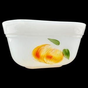 May include: White ceramic mixing bowl with a hand-painted yellow and orange fruit design. The fruit has green leaves.