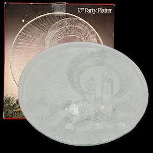 Puede incluir: Una fuente de fiesta de vidrio transparente de 33 cm con un diseño en relieve que presenta dos velas, una pancarta y agujas de pino. La fuente está frente a una caja con las palabras "13" Party Platter".