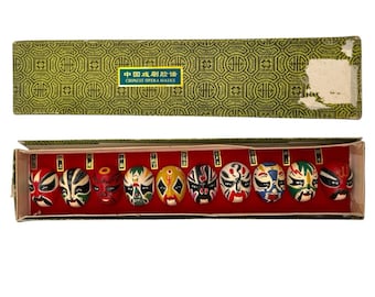 Juego de miniaturas de máscaras de ópera china de los años 70-80 en caja, montadas sobre terciopelo (10 unidades).