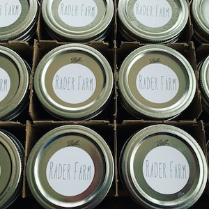 May include: A close-up of ten silver Ball brand canning jars with white labels that read "RADER FARM".