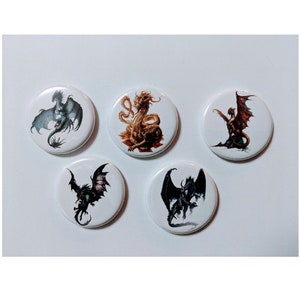 May include: Five white round buttons with dragon illustrations. The dragons are depicted in various colors, including black, gray, and red, with detailed wings and scales. The buttons are arranged on a white surface.