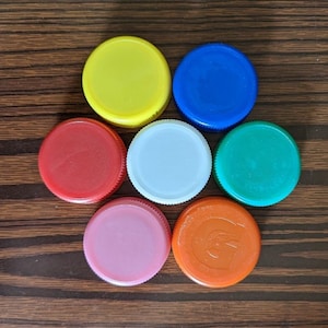 May include: Seven plastic bottle caps in a circle, with colors red, yellow, blue, green, white, pink, and orange.