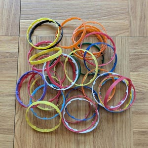 May include: A pile of colorful plastic rings, some with white edges, in various shades of red, orange, yellow, green, blue, and black.