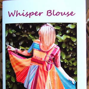 May include: A colorful striped blouse with short sleeves and a loose-fitting scoop neck. The skirt is made of multiple pieces of fabric, creating a fluttering effect. The blouse is shown on a model in a garden setting. Sizes XSM-4X. Tissue pattern pieces included. Whisper blouse has short sleeves and a loose-fitting scoop-necked bodice. The fluttering skirt pieces fall to a flattering length right below the hips. Make every piece different as shown above or use all one fabric.