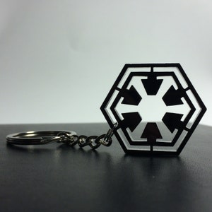 Peut inclure: Un porte-clés noir et blanc représentant le symbole de l'Empire galactique de Star Wars. Le symbole est un hexagone avec une étoile à six branches à l'intérieur.