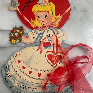 May include: Vintage Valentine's Day card featuring a cartoon girl with blonde hair, holding a bouquet and a heart-shaped purse. The card has a red heart-shaped top with the text "MY VALENTINE". The dress is cream-colored with red hearts and the text "I'M A LITTLE GADABOUT WHO IS ALMOST MAD-ABOUT-YOU."