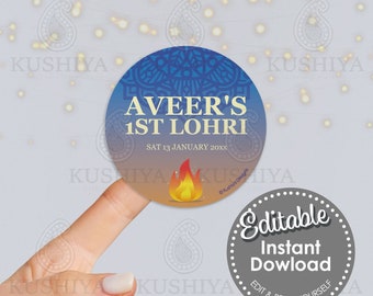 May include: A blue and orange circular sticker with the text "AVEER'S 1ST LOHRI" and "SAT 13 JANUARY 20XX". A small fire icon is in the bottom center of the sticker. The sticker is on a finger.