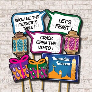 May include: A set of 7 Ramadan photo booth props. The props include a mosque, lanterns, gifts, and speech bubbles with text such as "Show me the desserts table!" and "Let's feast!"