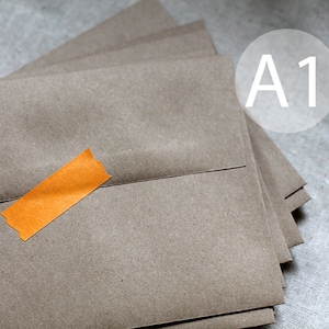 May include: A stack of brown paper envelopes with a single orange piece of tape on the top envelope. The text "A1" is written in white on a white circle.