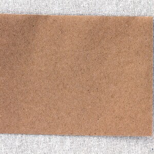 May include: A brown paper card with a rough texture. The card is blank and ready for writing or drawing.