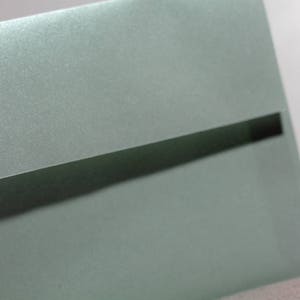 May include: A light green envelope with a black flap. The envelope has a subtle shimmery finish.