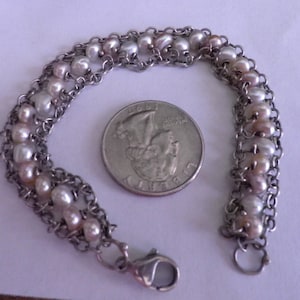 May include: A silver chain bracelet with a double row of white and pink pearls. The bracelet has a lobster clasp closure.