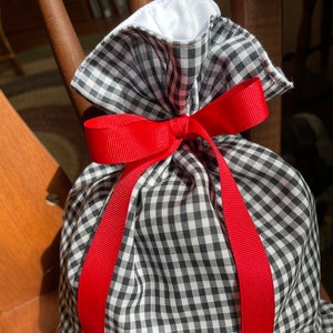 May include: A black and white gingham gift bag with a red ribbon tied around it.