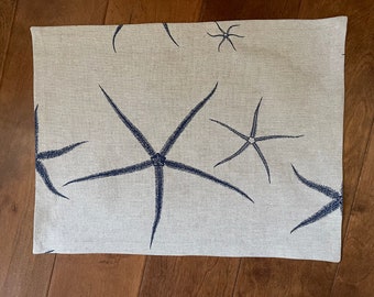 Placemats, set of 6, in a soft beige with blue starfish design, 12 1/2 x 16 1/2 inches, coastal theme.