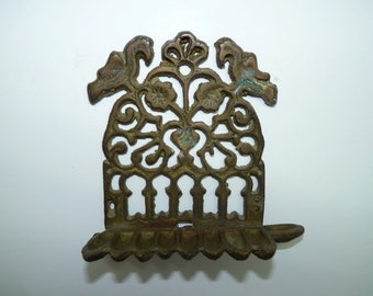 May include: A brass menorah with a decorative design featuring birds and floral motifs. The menorah has seven candle holders and a base with a scalloped edge.