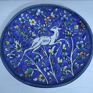 Könnte beinhalten: Ein blauer und weißer Keramikteller mit einem Blumendesign und einem weißen Reh in der Mitte.