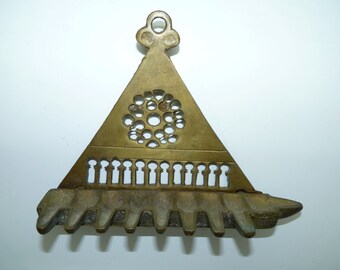 May include: A brass menorah with a triangular base and a decorative top. The menorah has 9 candle holders and a central design with a circle of holes.