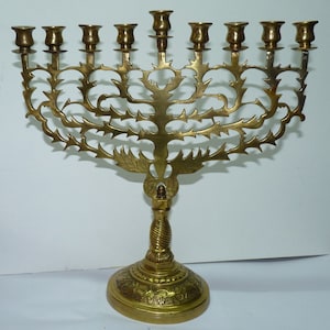 May include: A gold menorah with a tree-like design and a twisted base. The menorah has nine candle holders and is decorated with intricate details.