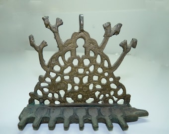 May include: A brass menorah with a decorative, intricate design. The menorah has seven candle holders and a central arch.