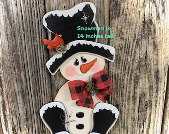 Puede incluir: Decoración de muñeco de nieve de madera, 35,5 cm de altura, con sombrero de copa negro y pies negro carbón. Tiene un lazo a cuadros rojo y negro, una nariz de zanahoria y un cardenal rojo. El texto dice: "Snowman is 14 inches tall."