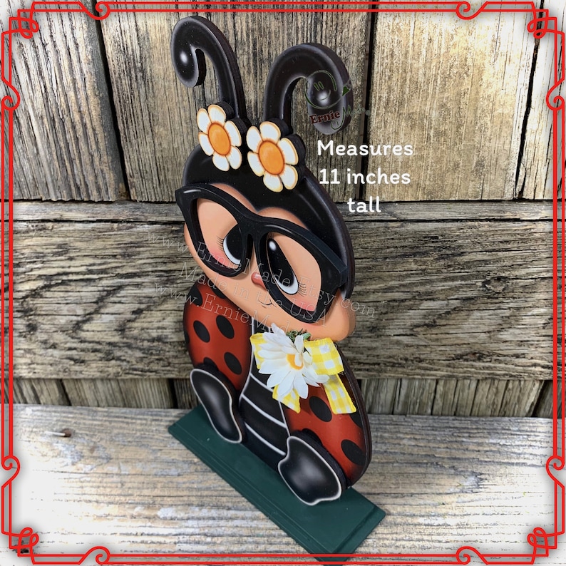 May include: A wooden ladybug figurine with black glasses, red and black wings, and white flowers. It measures 11 inches tall.