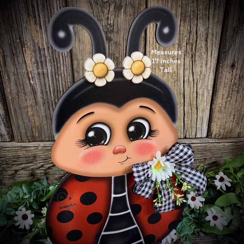May include: A hand-painted wooden ladybug with black and red details, large eyes, and a white daisy bow. The ladybug is 17 inches tall. Measures 17 inches Tall.