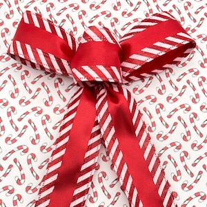 May include: A red and white striped ribbon bow tied on a white background with a repeating pattern of red and white candy canes.