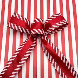 May include: A red and white striped ribbon bow tied on red and white striped wrapping paper.