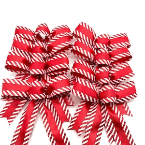 May include: A set of six red and white striped bows with a glittery finish. The bows are tied with a loop and tails.