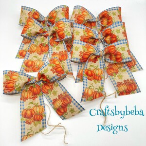 May include: Six handmade burlap bows with a blue and white gingham trim and a pumpkin print. The bows are tied with twine and have a rustic fall theme. Craftsbybeba Designs.